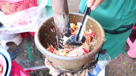 preparing papaya salad in a traditional thai mortar