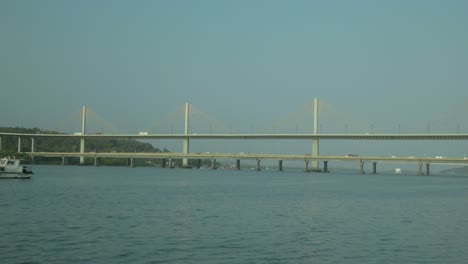 wide shot of a bridge over a river with a yacht passing underneath in daylight