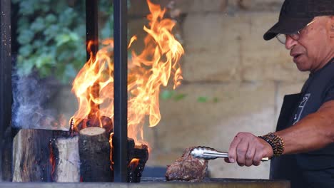 man grilling meat over a wood fire