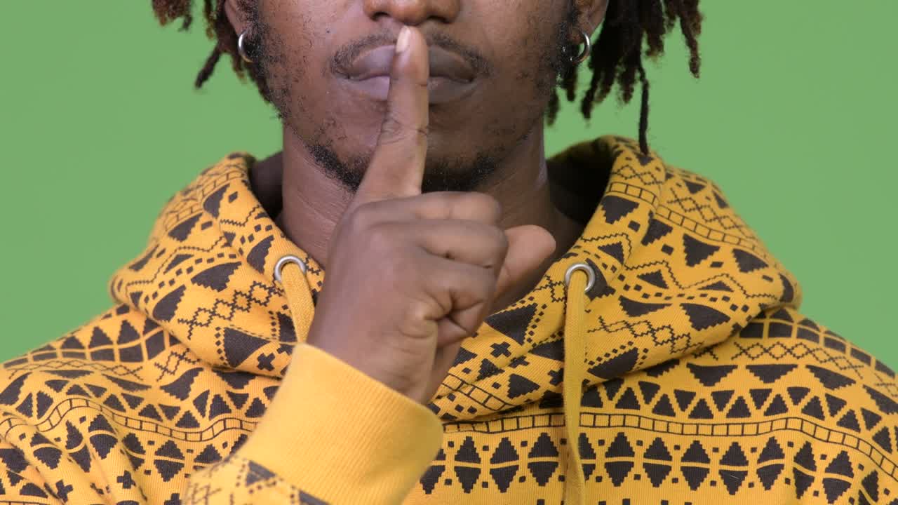 Young handsome African man with finger on lips