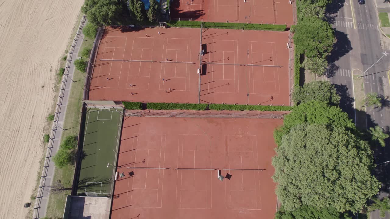 Vista aerea di un complesso tennistico in città, con un rigoglioso boschetto di alberi