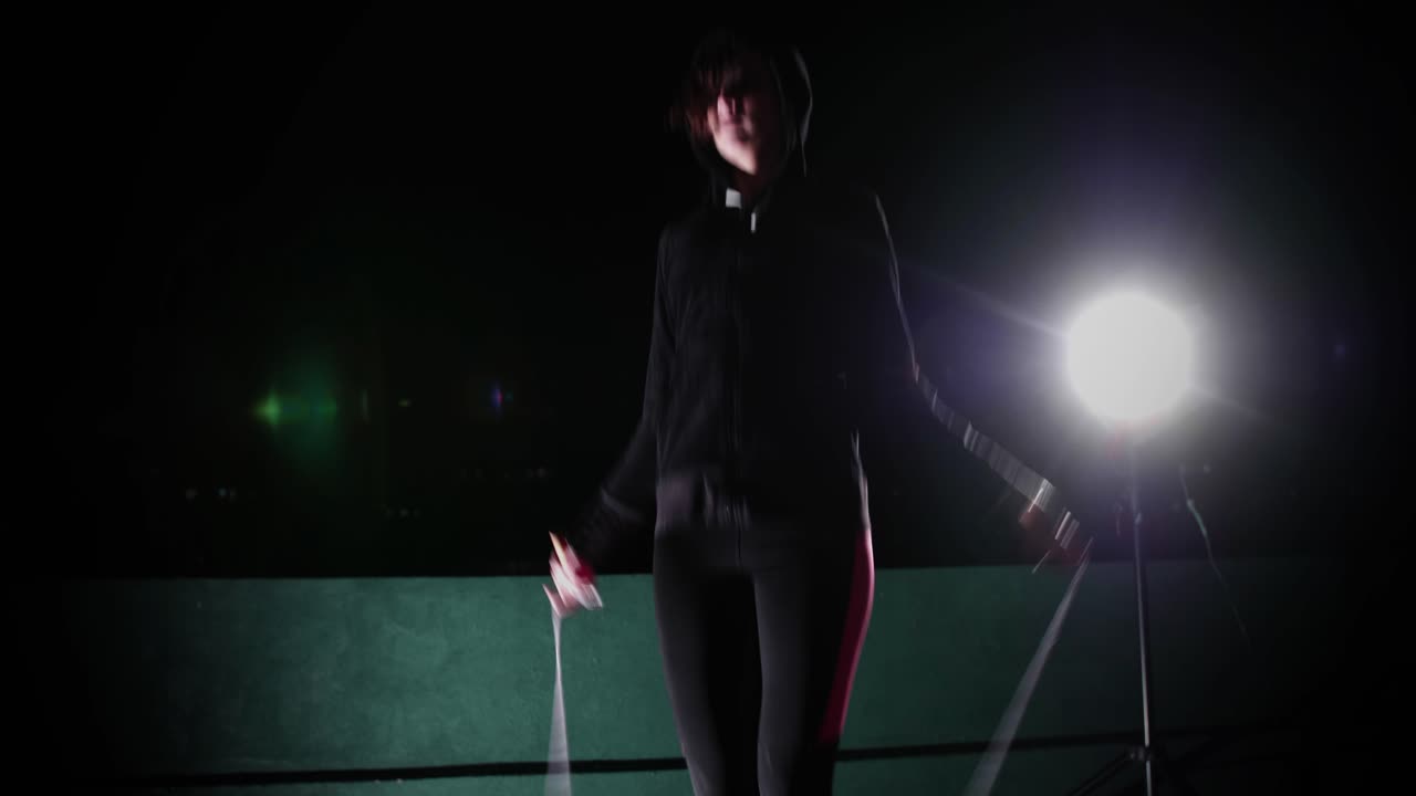 Donna giovane che salta la corda con controluce drammatico di notte
