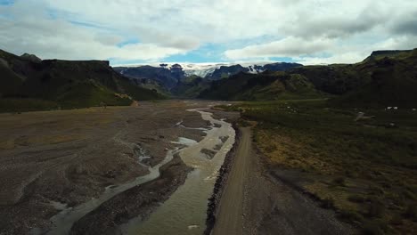 Vista-Aérea-Del-Paisaje-De-Un-Río-Que-Fluye-A-Través-De-Un-Valle,-Junto-A-Una-Carretera,-En-El-área-De-Fimmvörðuháls,-Islandia