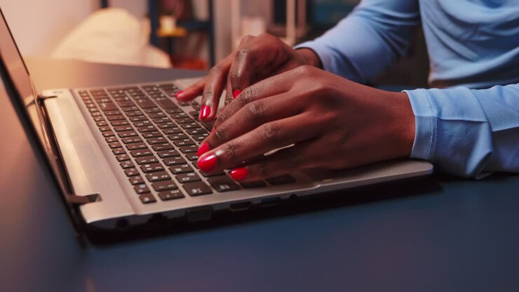 Nahaufnahme einer schwarzen Frau, die auf der Tastatur eines Laptops tippt