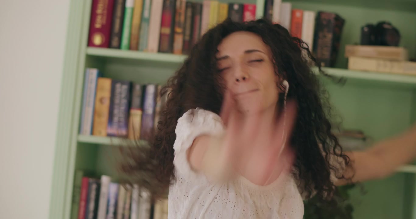 Woman dances at home with arms raised up