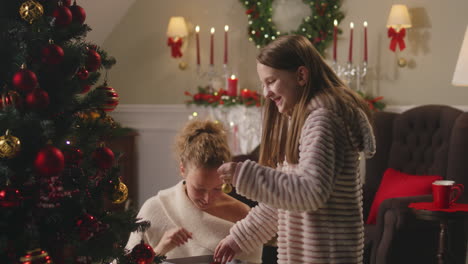 sisters decorating christmas tree and opening gifts