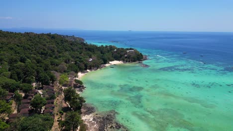 Aerial-view-of-a-tropical-island-beach-with-turquoise-water-showing-long-tail-boats-waiting-for-tourists-in-thailand