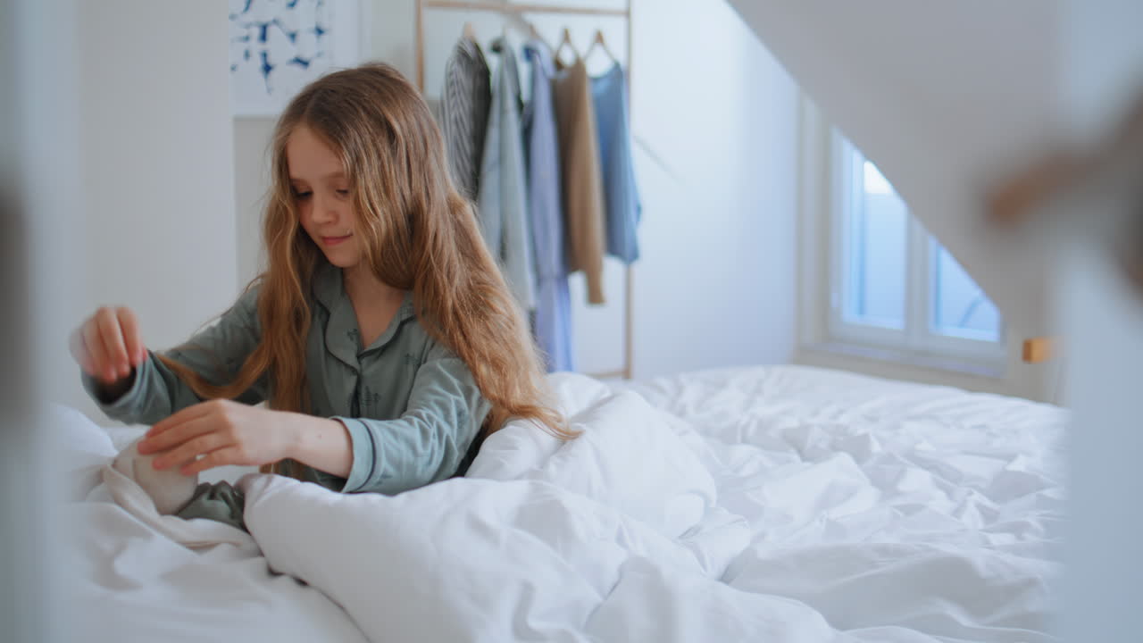 Little girl playing plush toy at bedroom closeup. Carefree child having fun