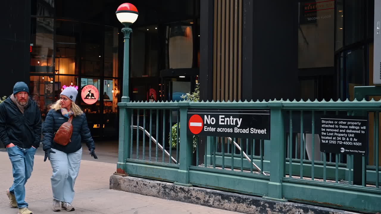 New York, USA, 5 dicembre 2025: tre persone passano davanti al corrimano dell'entrata della metropolitana