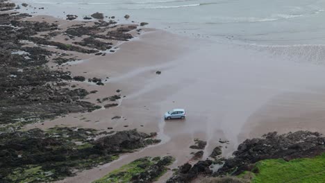 car parked on sleeping bay sandy beach cove in milford haven aerial view looking down from cliff