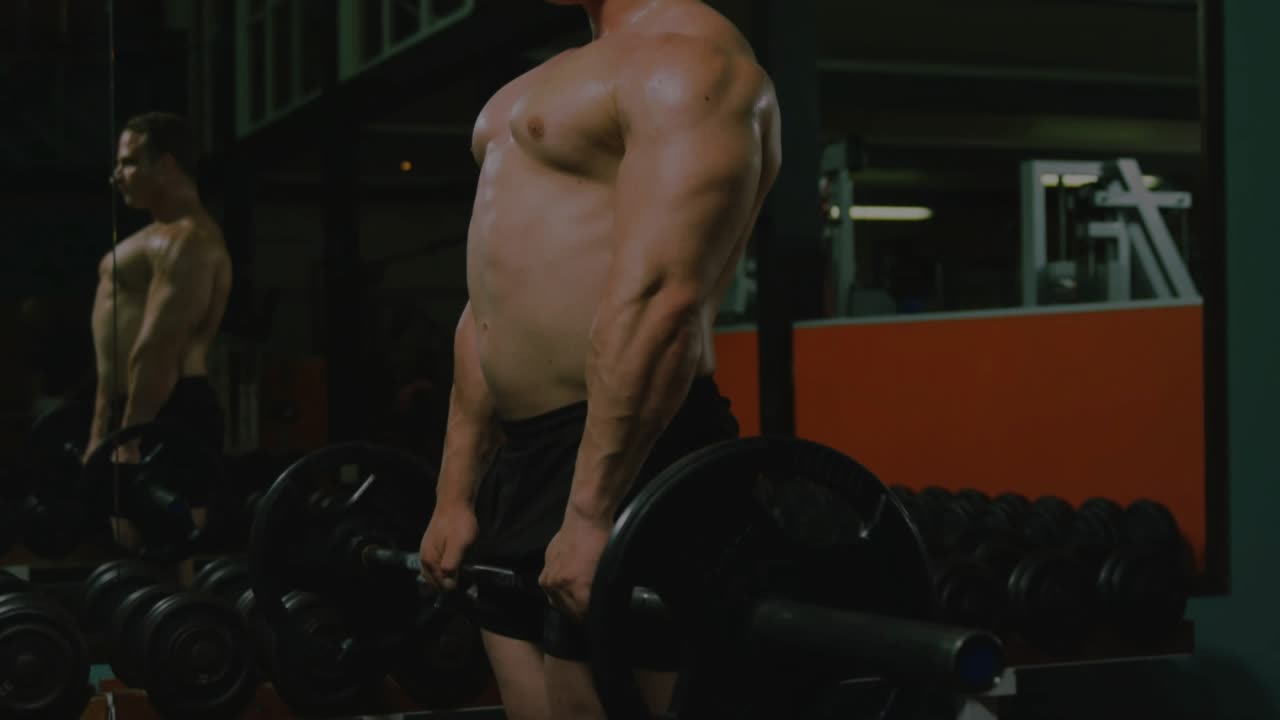 Man starting deadlifts at gym lowering and driving barbell as numeric overlay appearing over mirror