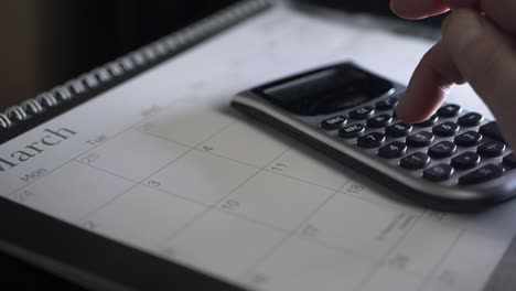 hands using calculator on march calendar medium panning shot