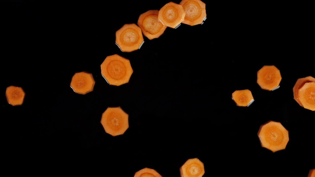 Pezzi di carota fresca che cadono in acqua