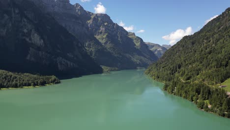 aerial footage captures a breathtaking scene of a large peaceful lake surrounded by mountains hills and trees lush greenery clear blue water create a vibrant tranquil atmosphere perfect for adventure