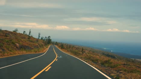 driving down towards the pacific ocean from mauna kea volcano in the afternoon light with lava flows visible in the background