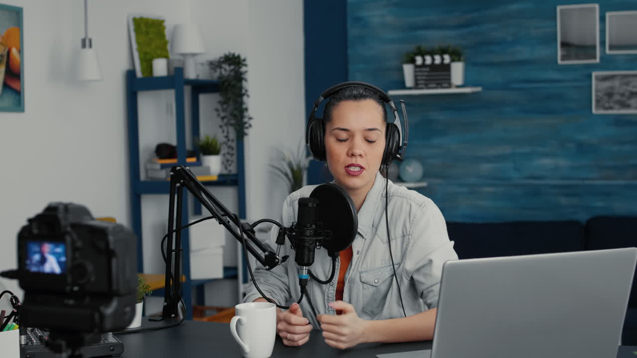 Populær skaber af digitalt indhold sidder ved sit skrivebord i hjemmestudiet og filmer en vlog