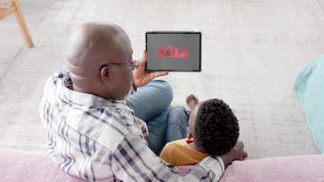 African-american-grandfather-and-grandson-using-tablet,-shopping-online-during-sale,-slow-motion