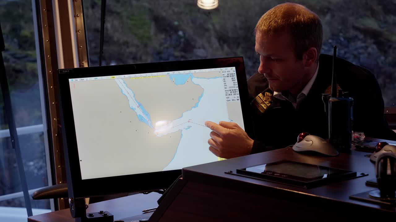 Captain showing voyage through Red Sea and Yemen on electronic map, worried