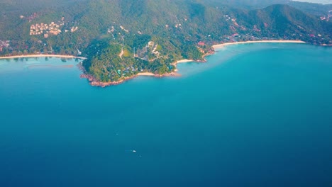 4k aerial drone push forward shot of salad beach on koh phangan in thailand with fishing boats, teal water, coral, and green jungles