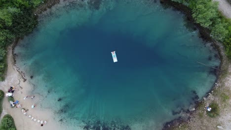 Adult-person-lying-on-floating-water-mat-at-Izvor-Cetina-spring,-Aerial