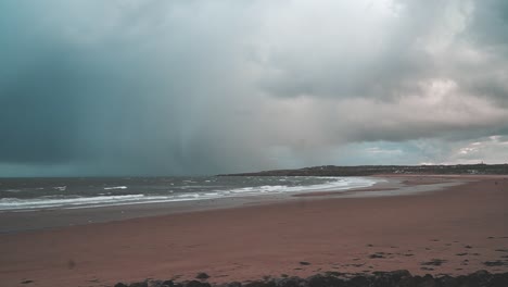 grey stormy rain clouds over an empty beach with waves crashing in south shields, uk