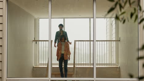 una pareja hablando en una escalera en una casa