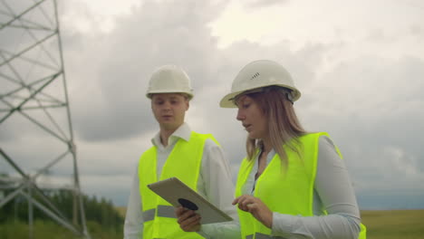 un electricista en los campos cerca de la línea de transmisión de energía. el electricista maneja el proceso de erigir líneas eléctricas. el mecánico en un casco