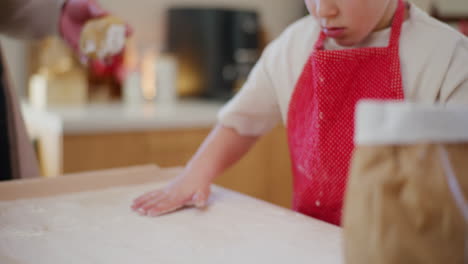 boy rubs flour on a board and prepares it for shaping dough