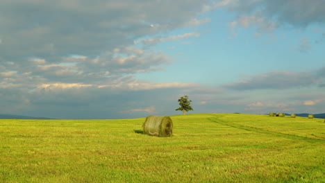 Hügel-Mit-Einem-Verlassenen-Baum-Während-Des-Tages-Mit-Blick-Auf-Einen-Heu--Oder-Strohstapel-Und-Blick-Auf-Wolken-Und-Die-Umliegende-Natur-Panorama-Landschaftsansicht-In-4k-60fps-Aufnahme