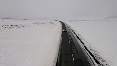 Aerial-front-view:-One-car-driving-on-on-a-snowy-road