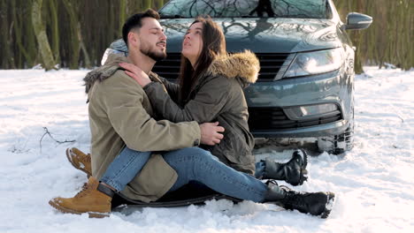 caucasian couple cuddling in the snow during a roadtrip.