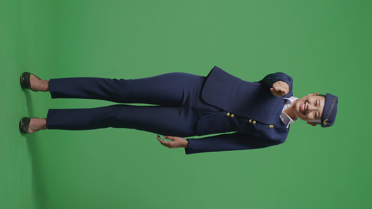 아시아 여성 항공 승무원이 웃고 가을 만지며 녹색 스크린 배경 스튜디오에 서있는 동안 당신을 가리키고 있습니다.