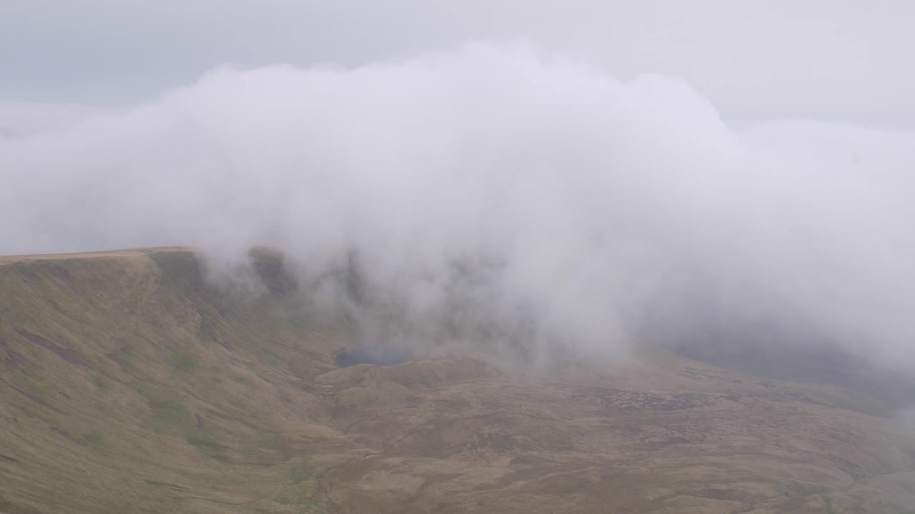 Clouds and fog slowly rolling over Pen y Fan in Brecon Beacon hills, Wales, UK 4K