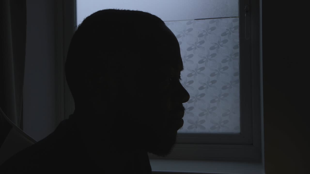 흑인 남성이 방에서 일하면서 음악을 듣고 있는 실루