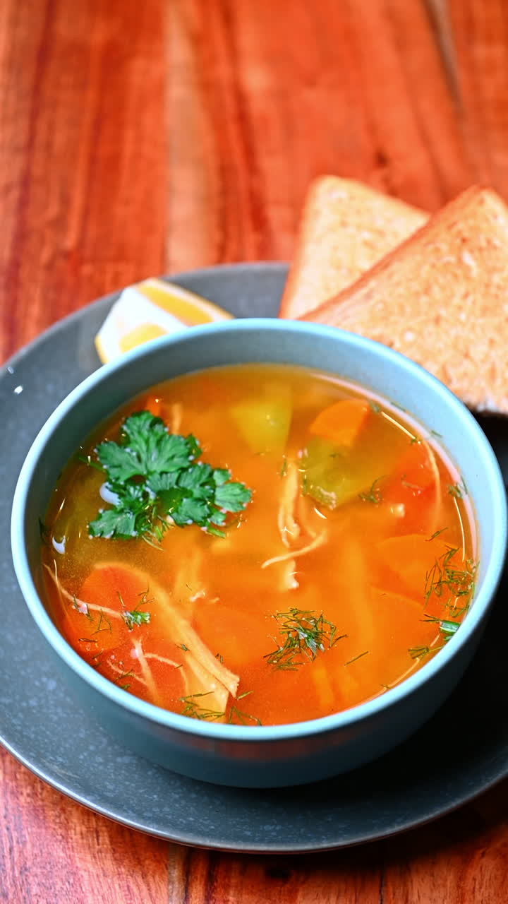 Lys suppe med grøntsager. Klar suppe med grøntsager og kyllingestykker på en tallerken