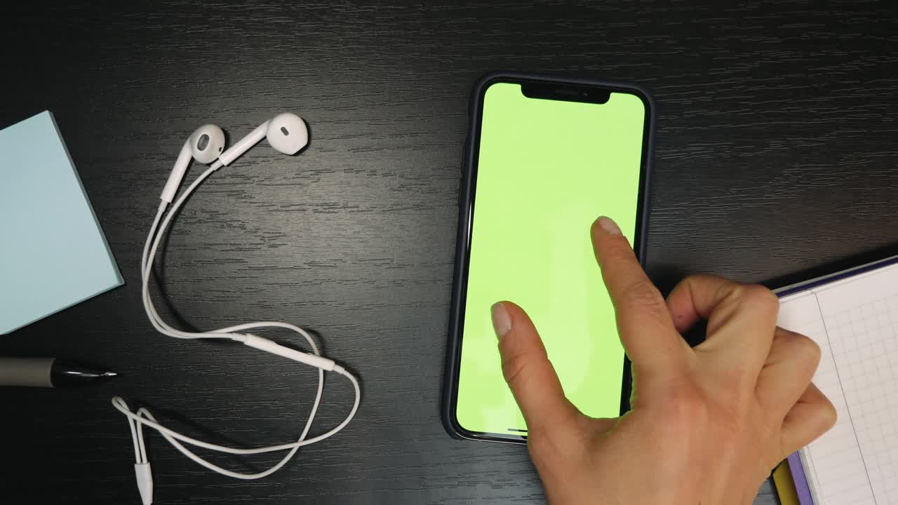 la mujer está usando un teléfono inteligente con pantalla verde en la mesa. los dedos están desplazando noticias, viendo fotos en las redes sociales. clave de croma
