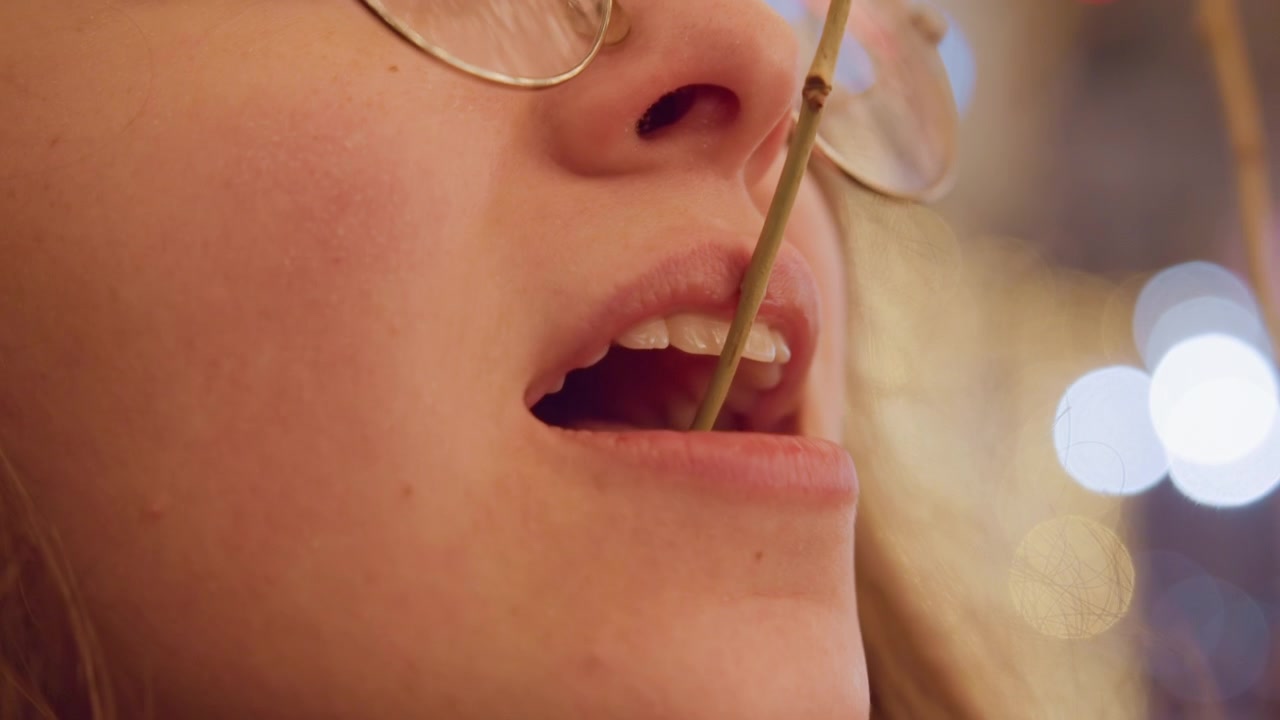 Ragazza vivace si gode lo scintillio delle feste. Giovane donna che assapora dolcetti tra vivaci decorazioni. Donna bianca vivace che esplora dolcetti festivi con energia gioiosa e luci brillanti e illuminanti
