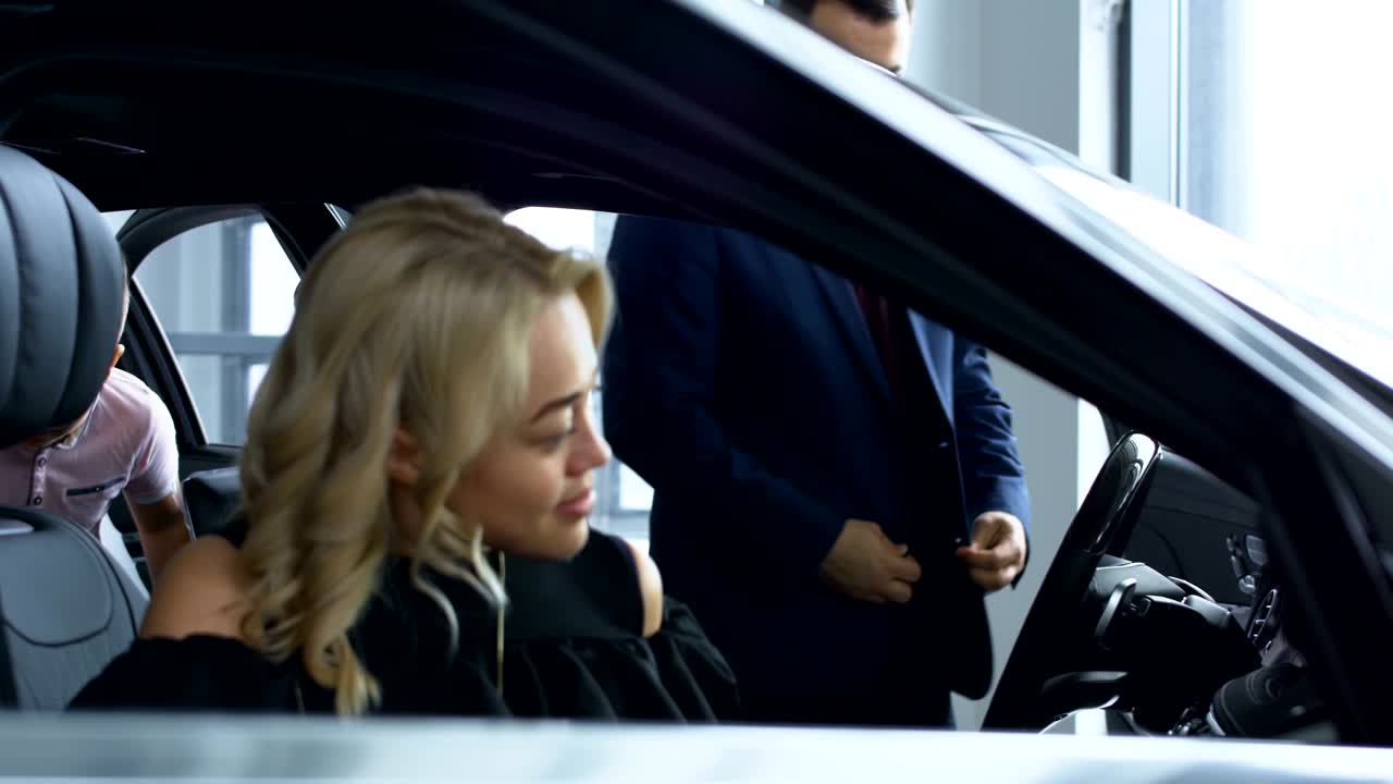 una pareja exitosa probando un nuevo coche en el salón.