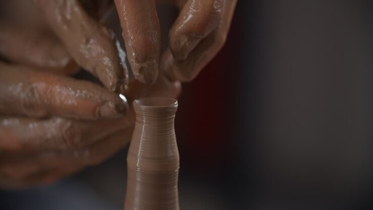 陶器 の 輪 に 粘土 を 形作っ て いる 手