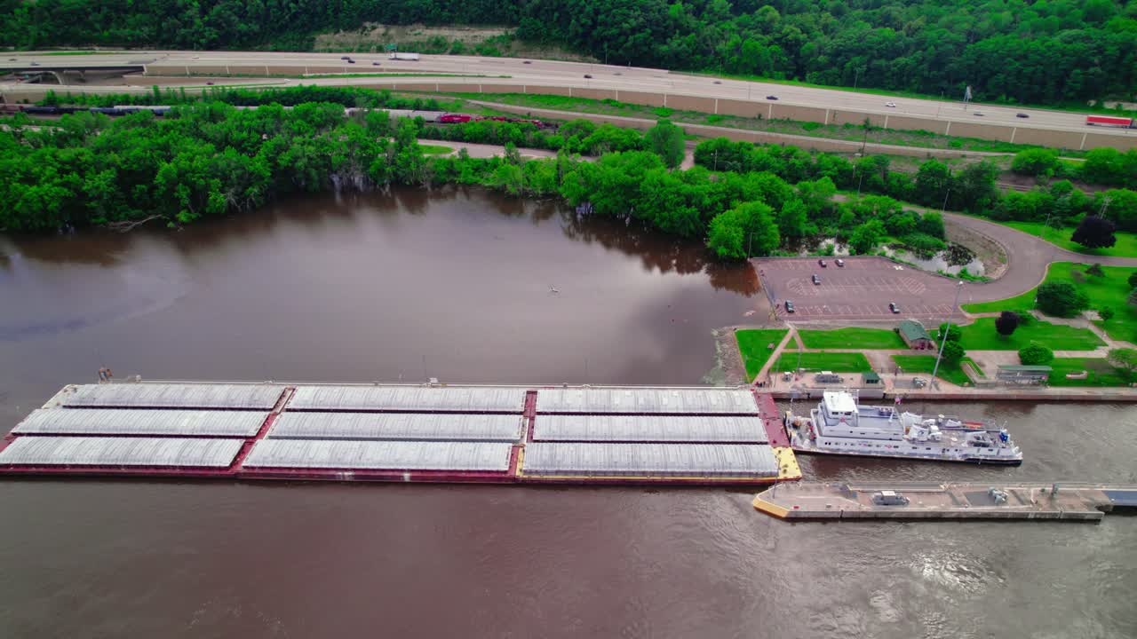 буксир, помогающий плоскодонному внутреннему водному суду, проходящему через систему шлюзов и дамб на реке миссисипи недалеко от ла-кресента, штат миннесота