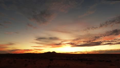 Golden-orange-and-pink-sunrise-over-Mojave-Desert-with-clouds-in-sky,-TIME-LAPSE