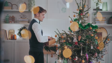 well dressed man hanging bauble on christmas tree at home