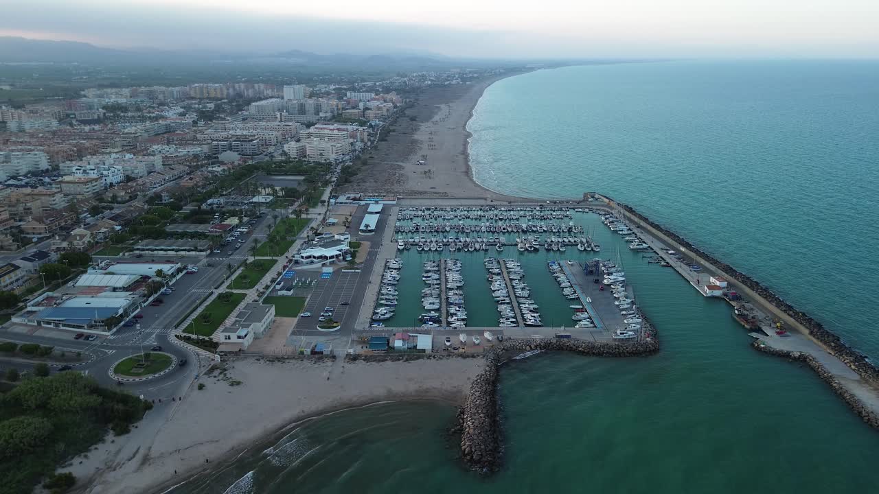 retiro de una marina costera al atardecer, con el horizonte de la ciudad y las montañas