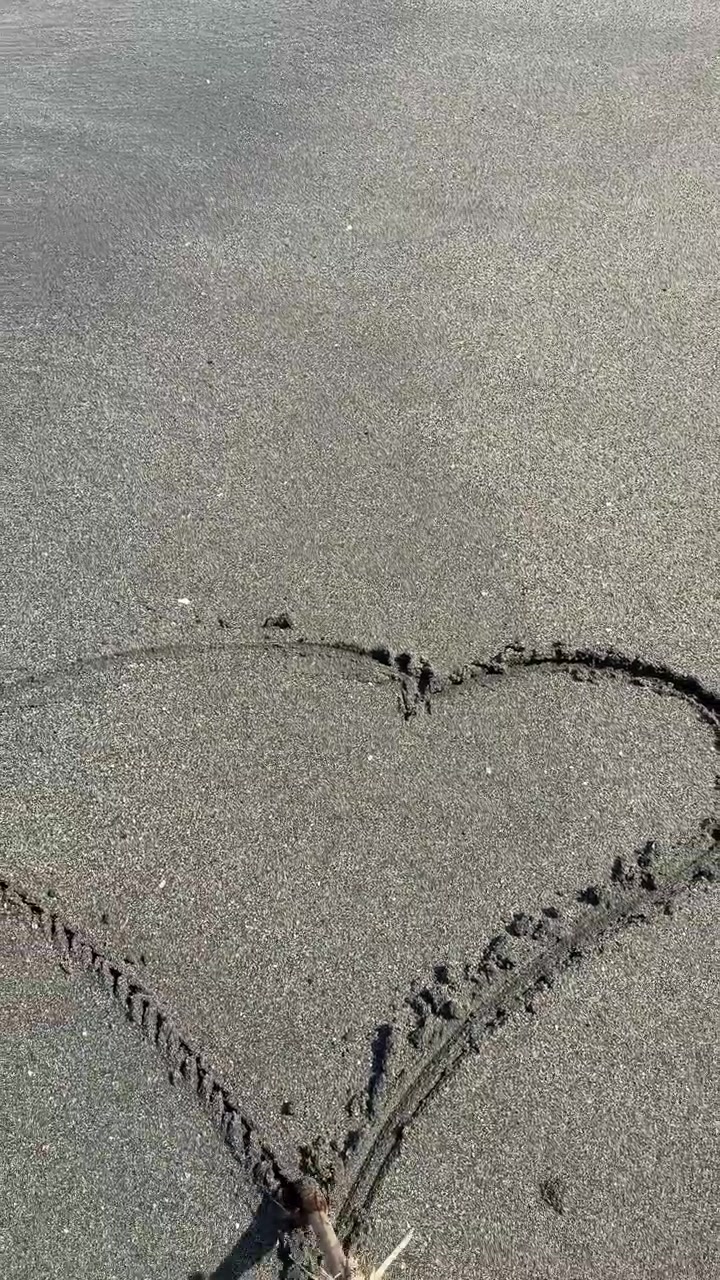 Drawing a Heart Shape in the Sand on the Beach