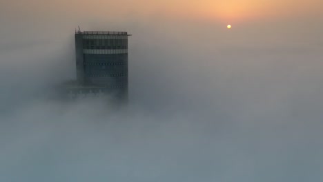 sunrise over a city tower in fog