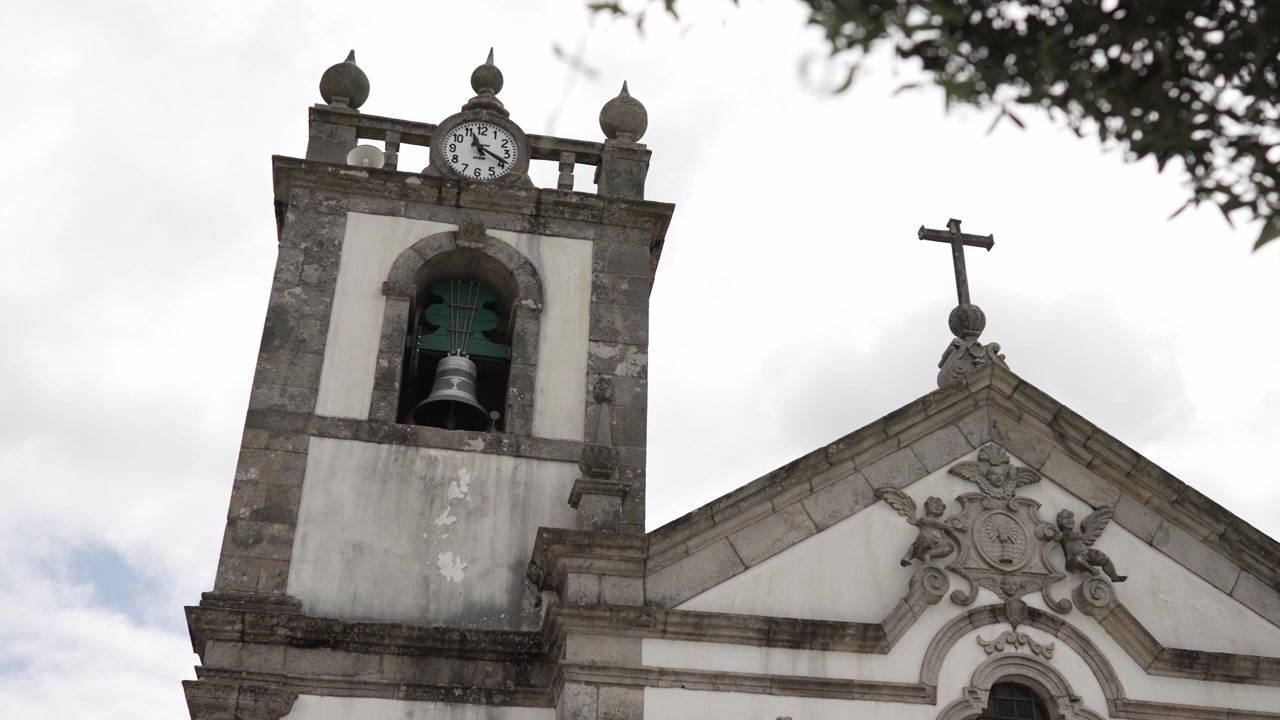 Primo piano di un tradizionale campanile di chiesa e croce sotto un cielo nuvoloso