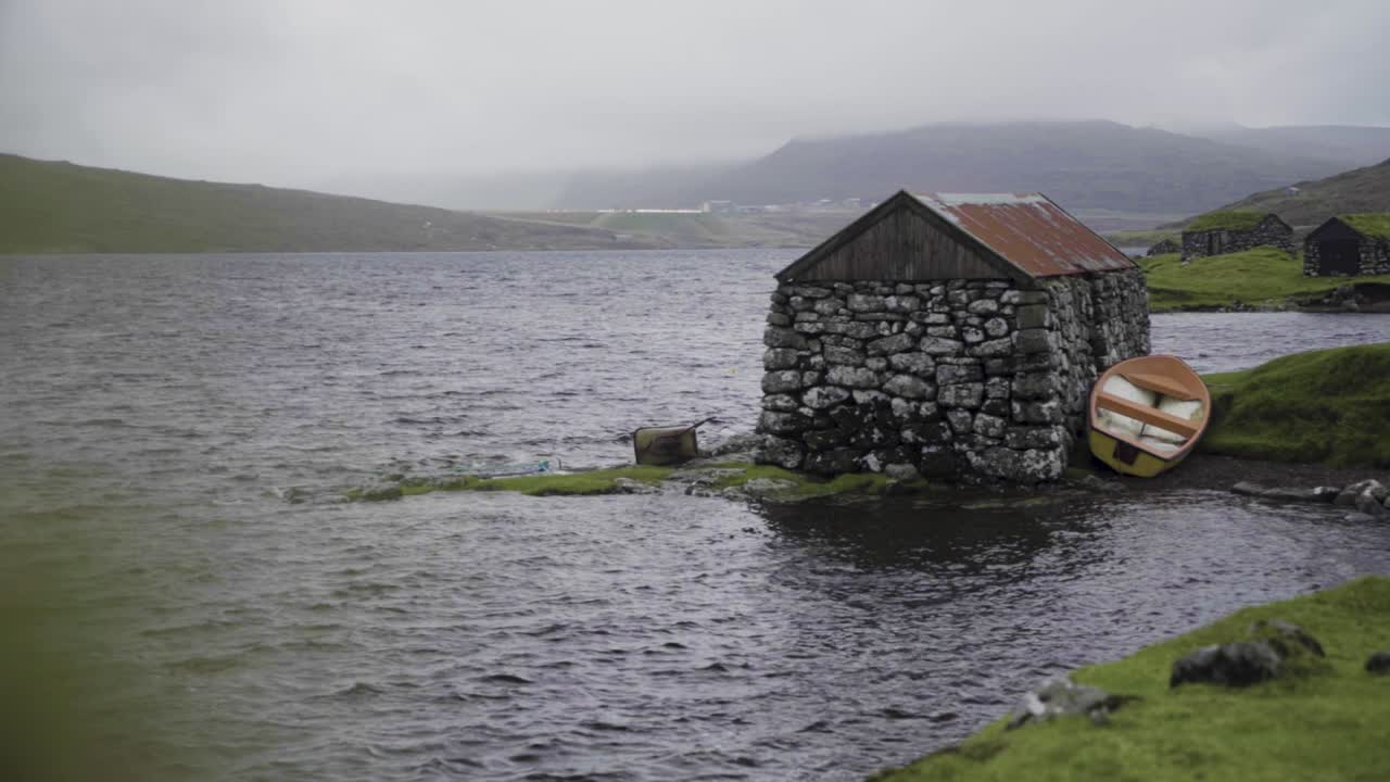 페로 제도 의 구름 은 날 에 자연 호수 연안 에 있는 오래된 돌 로 된 버려진 건물 의 넓은 사진
