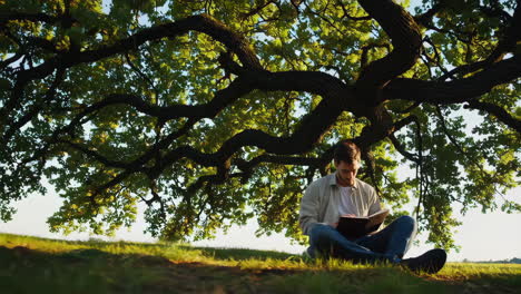 young man looking up at a tree in nature