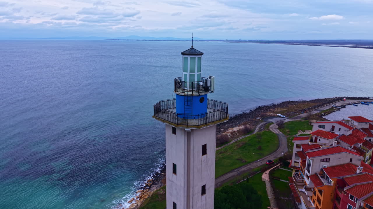 Il faro si erge su una costa rocciosa con onde oceaniche e cielo nuvoloso sullo sfondo.