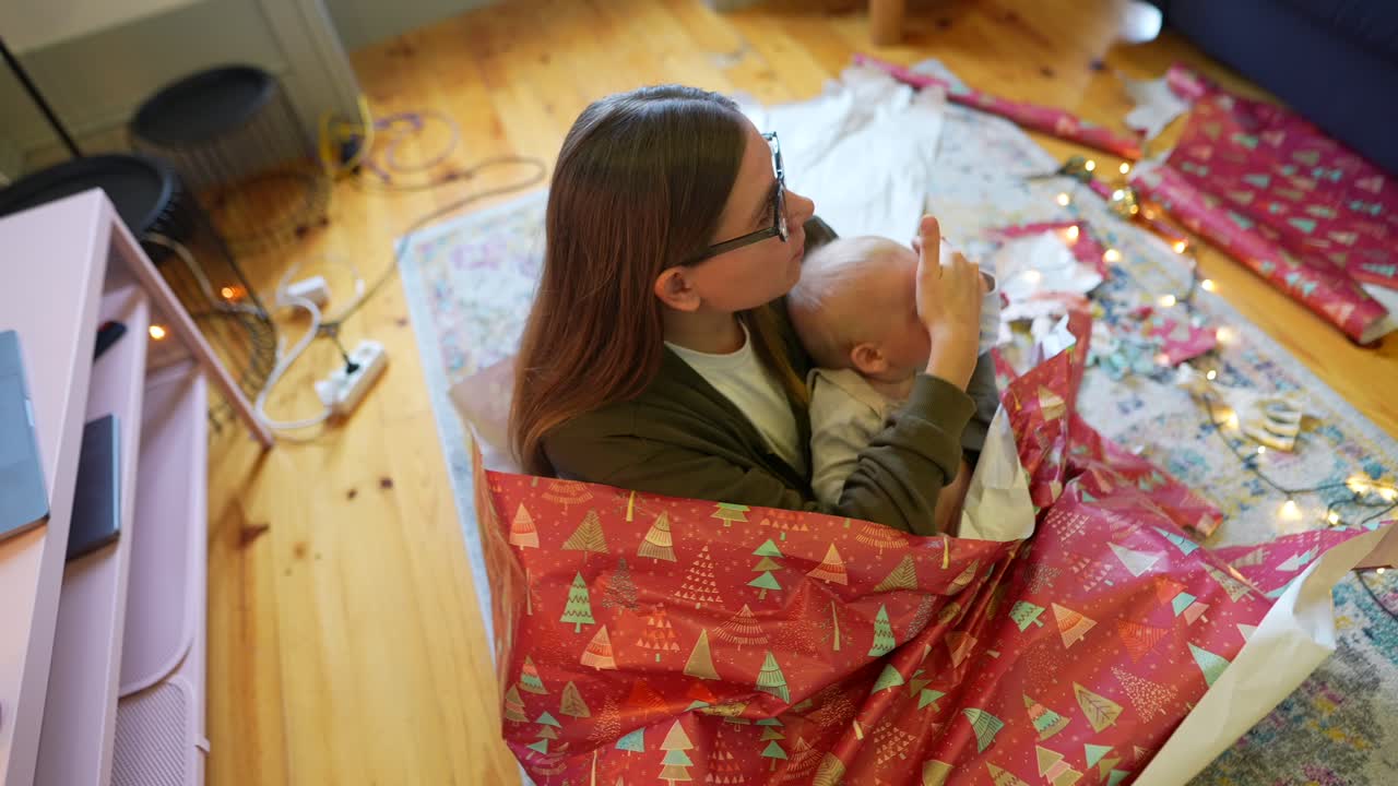 어머니 와 아기 가 크리스마스 선물 을 풀고 있다